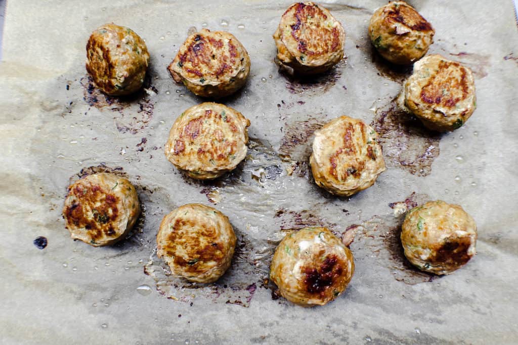 Cooked meatballs on a sheet of parchment paper. 