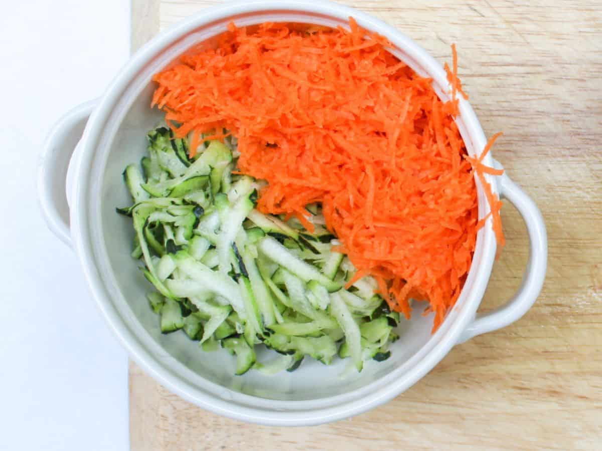 A white bowl with shredded zucchini and carrots.