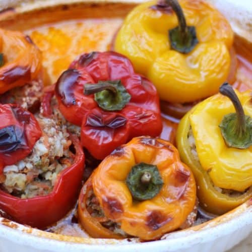 baked orange, yellow and red stuffed belln peppers in a baking dish.