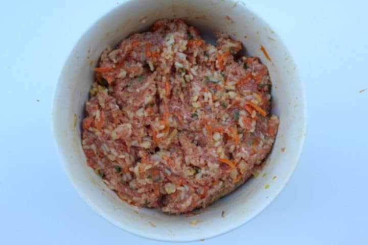 bell pepper stuffing mix in a white bowl: vegetables, cooked rice, raw beef, salt spicies. 