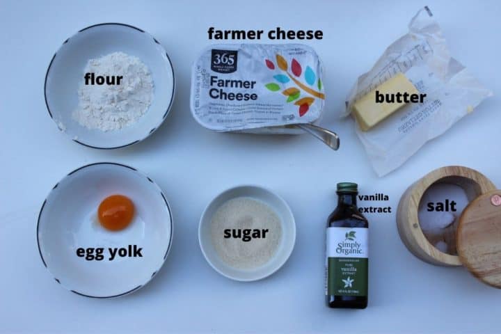 Measured ingrients laid out on a white background:flour, farmer cheese, butter, egg yolk, sugar, vanilla extract, salt