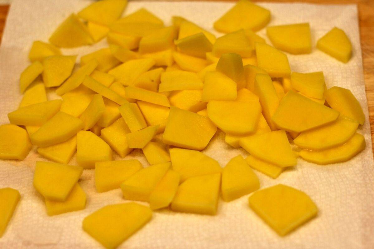 Sliced potatoes scattered on top of paper towels for drying.