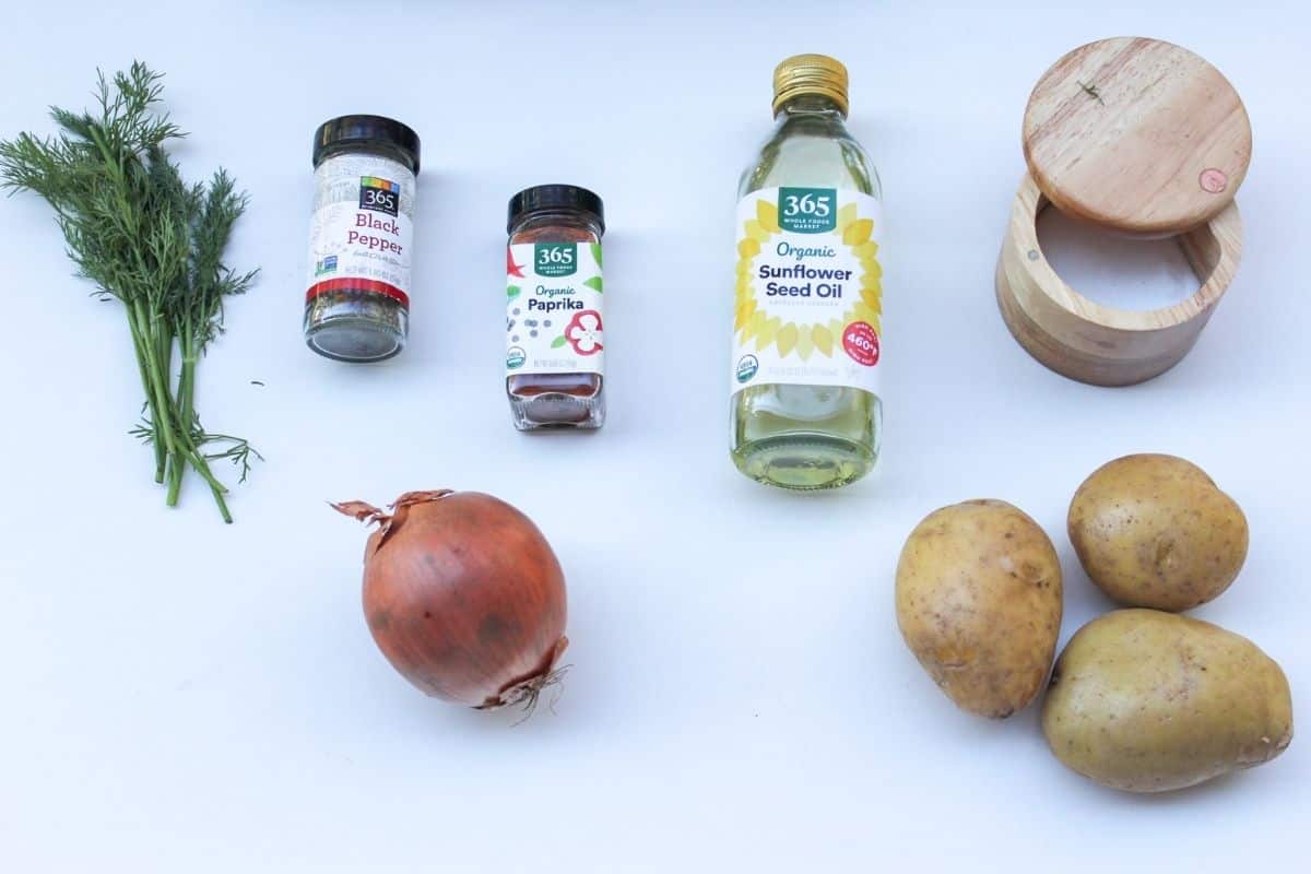 Recipe ingredients for pan-fried potatoes and onions made with three Yukon gold potatoes, yellow onion, oil, salt, paprika, black pepper and fresh dill. 