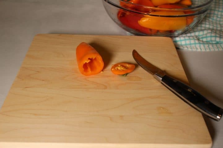 Process shot: a bell pepper on a cutting board with the top cut off and seeds removed.