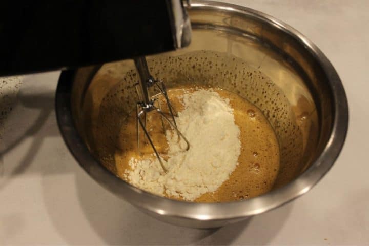 Large mixing bowl with mixer inserted into the cake mix.
