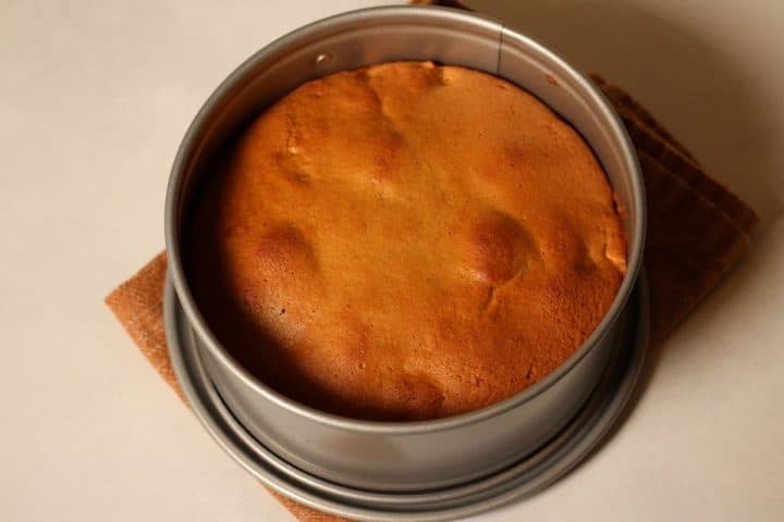 Overheat shot of a cooked gluten-free apple cake in a cake pan, on a brown napkin.