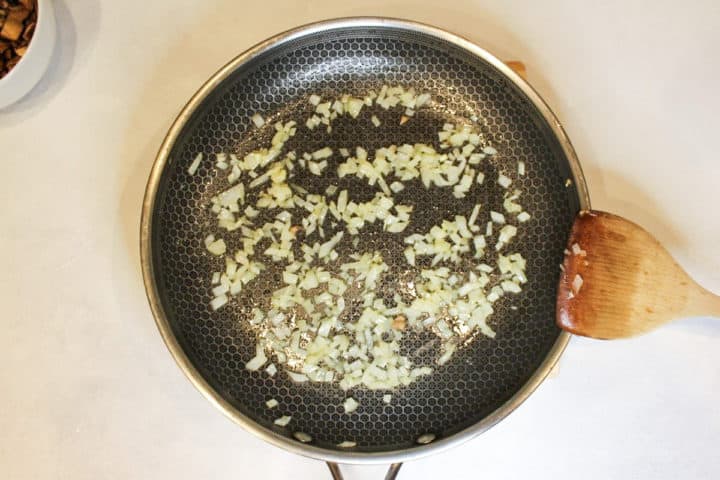 Frying pan with cooked diced onions in it.