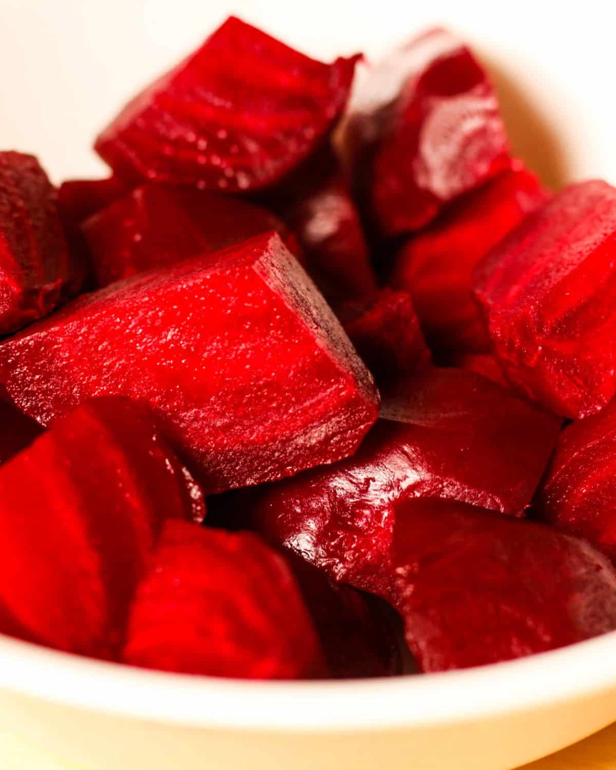 Instant Pot cooked red beets cut into chunks in a white bowl.