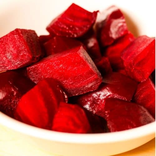 Cooked, peeled and cubed red beets in a white bowl.