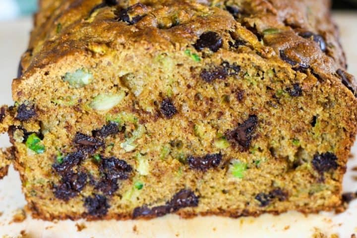 Close up shot of cut zucchini bread with visible chocolate chips, pumpkin seeds and shreds of zucchini inside.