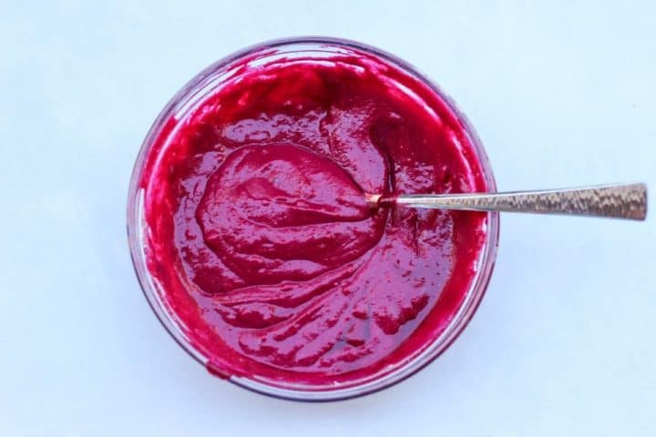 A glass mixing bowl with the bright red batter for beets waffles.