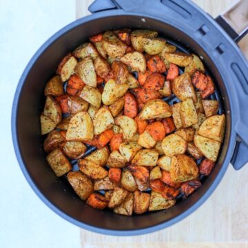 Seasoned and cooked potatoes and carrots in air fer basket.