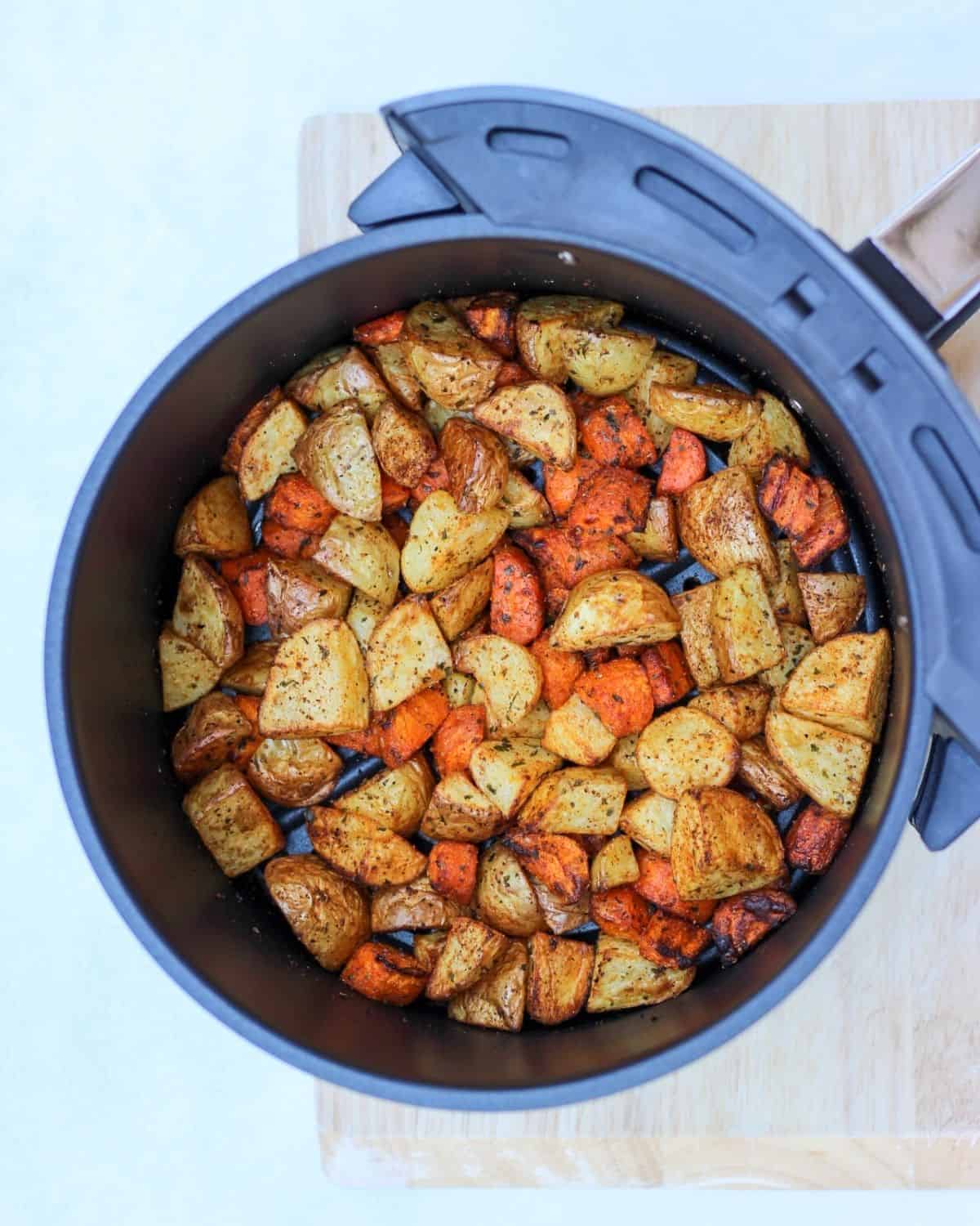 Cooked rir fyer carrots and potatoes in a round airfyer basket.