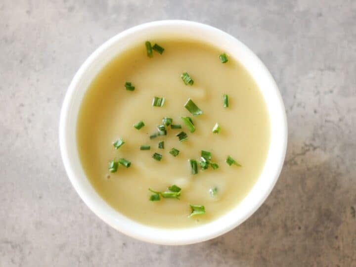 Creamy potato leek soup garnished with fresh green chives, served in a white bowl. 
