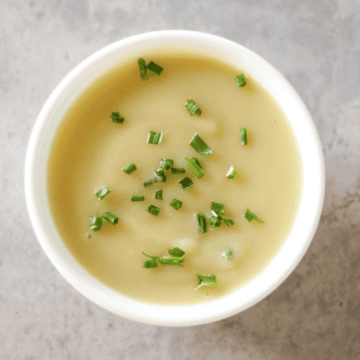 Creamy Instant Pot potato leek soup garnished with fresh green chives, served in a white bowl.