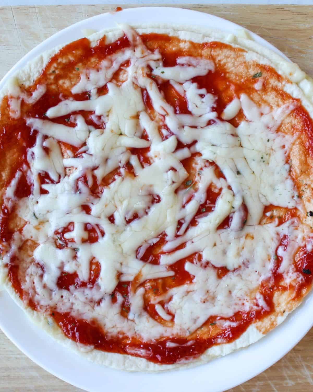 Tortilla pizza with red sauce and melted cheese on top.