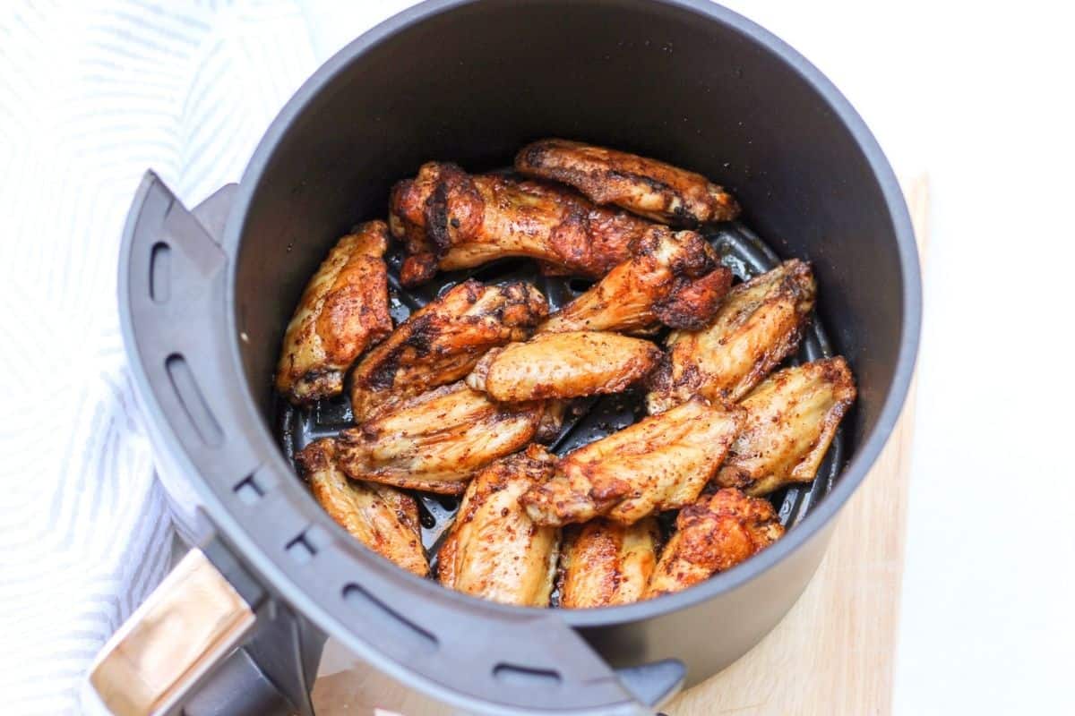 Process shot #3: overhead shot of air fryer basked with already cooked golden browned wings.