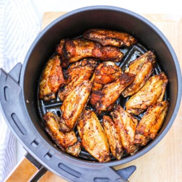 Overhead hero shot for the recipe. It shows the air fryer basked with already cooked golden-brown wings.