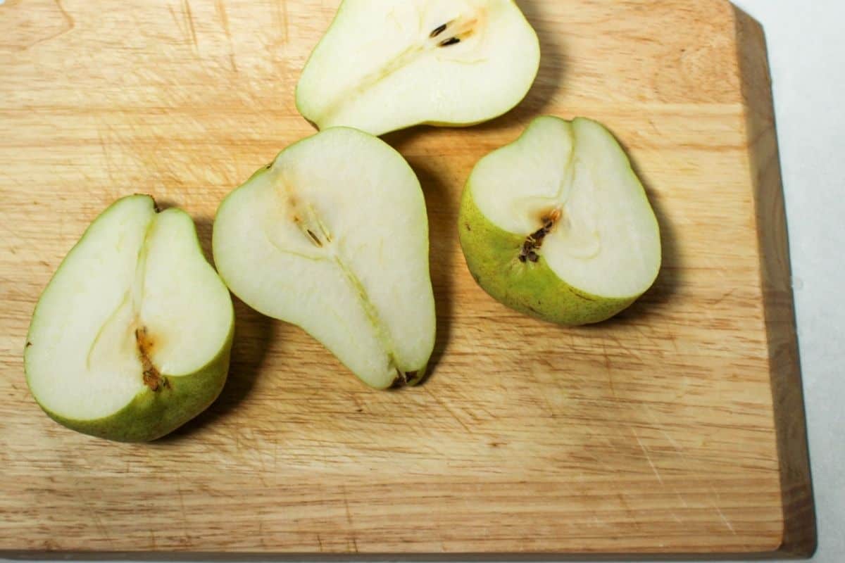 Process shot #1: 2 pears cut in halves laying on a wooden cutting board.