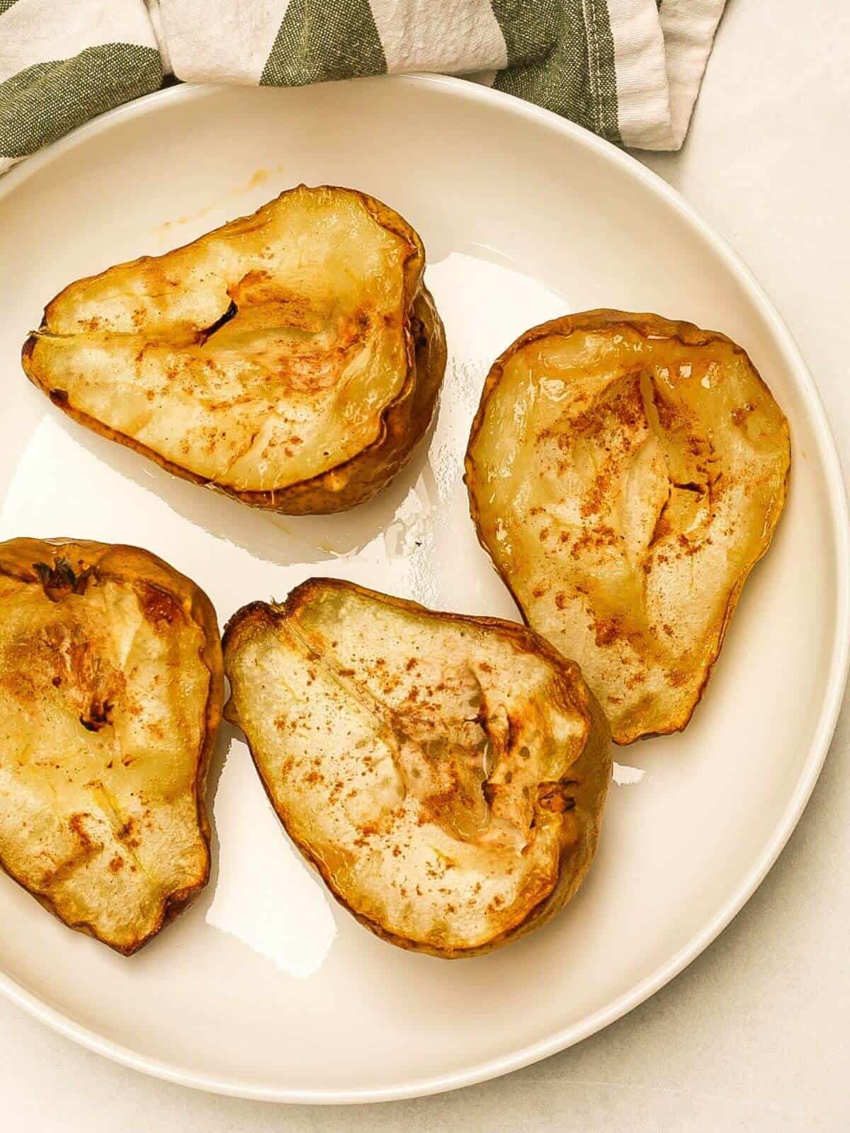 Over head shot of four caramelized pear halves on a white plate.