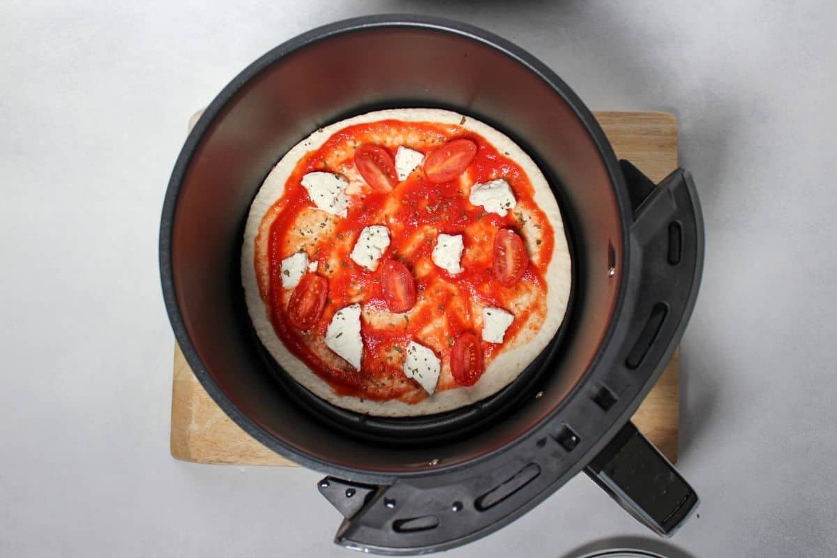 Goat cheese, spices and sliced cherry tomatoes added on top of pizza.