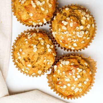 Overhead shot of 4 golden baked muffins on a white background.