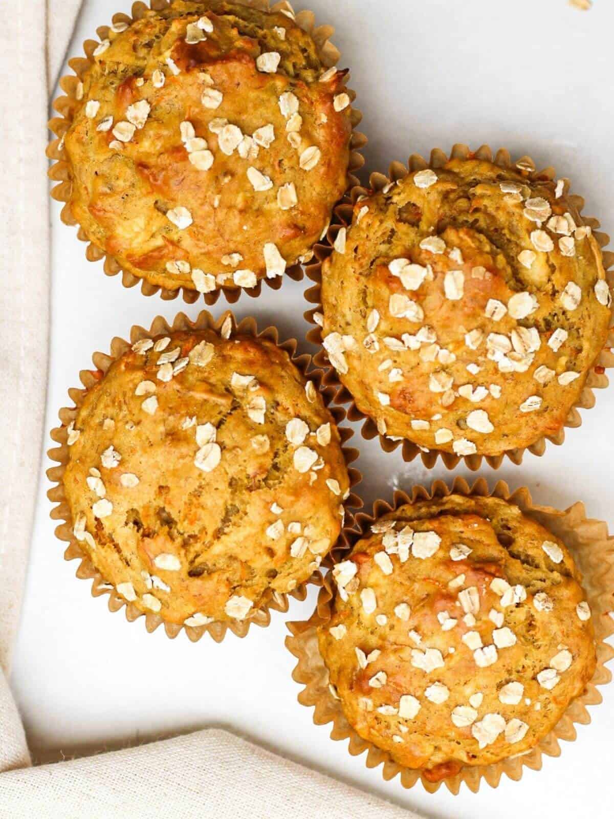 Overhead hero image of four golden muffins arranged on a white background.