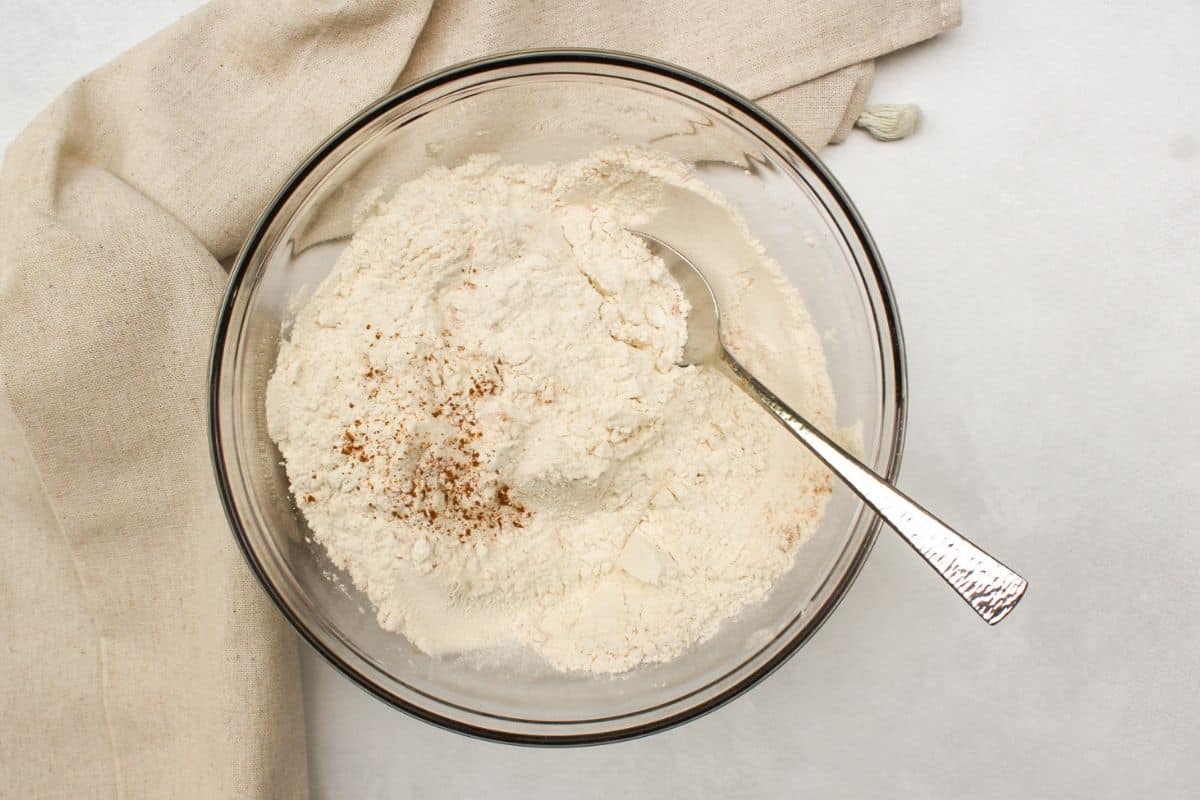 Process shot 1: a glass bowl with flour and visible sprinkles of cinammon on top