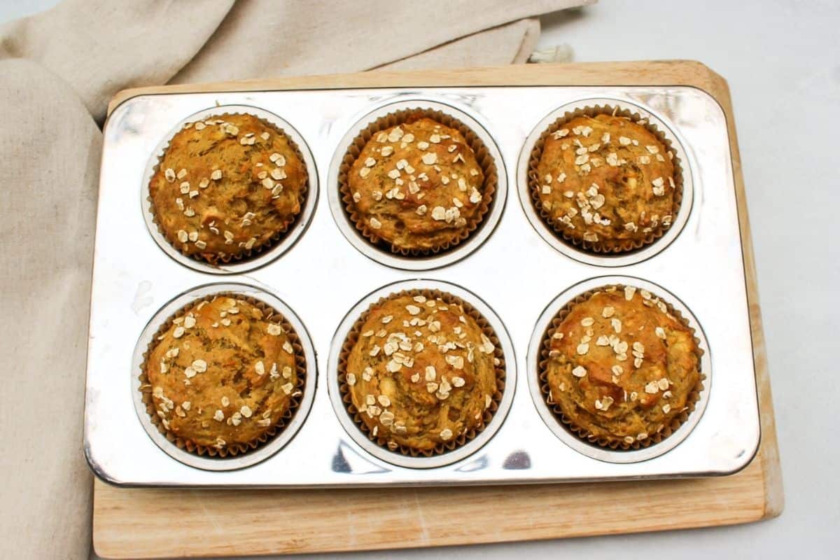 Overhead image of a 6 cup stainless stealmuffin pan with golden-brown baked muffins.