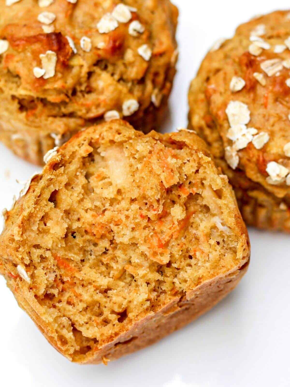 Close up overhead shot of halved moist golden muffin with vissible shredded carrots inside.