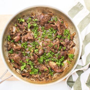 Cooked livers in afrying pan with fresh parsley on top.