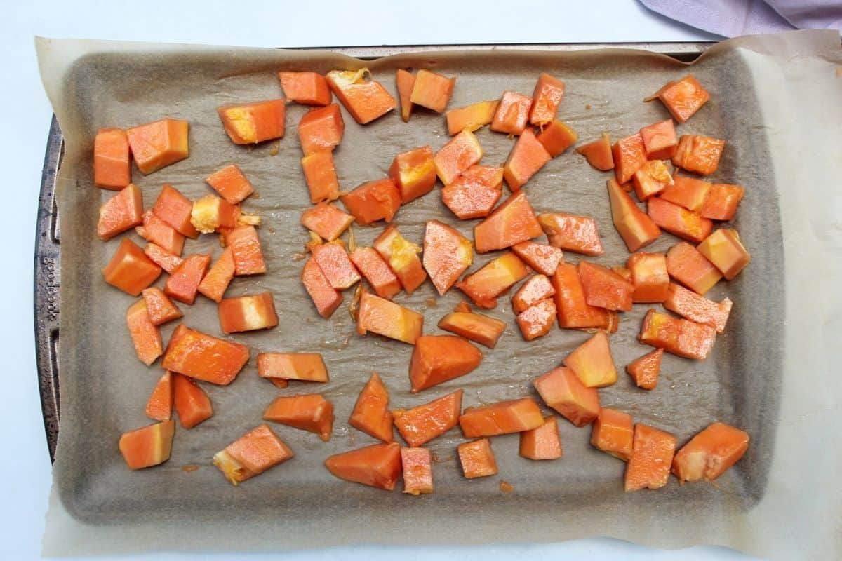 Process shot #3. Freshly cubbed papaya fuit spread on parchment paper.