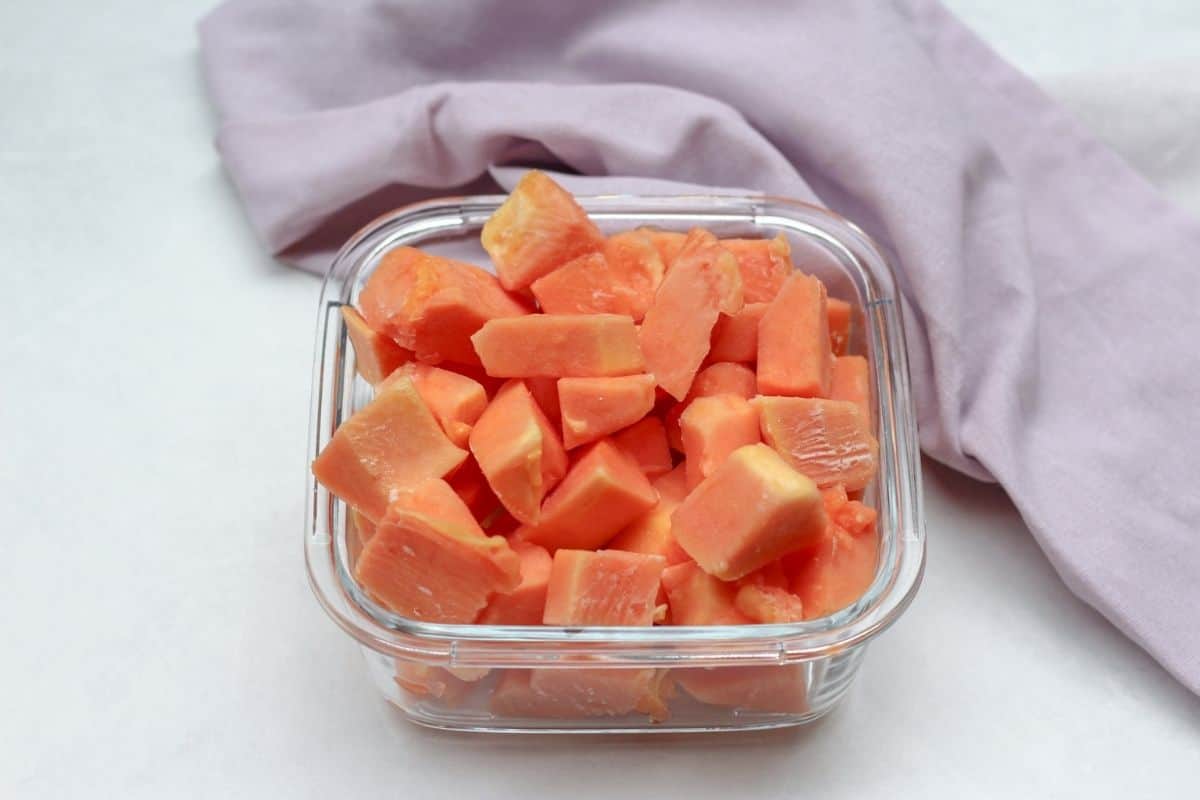 Frozen orange cubed fruit in a glass square container.