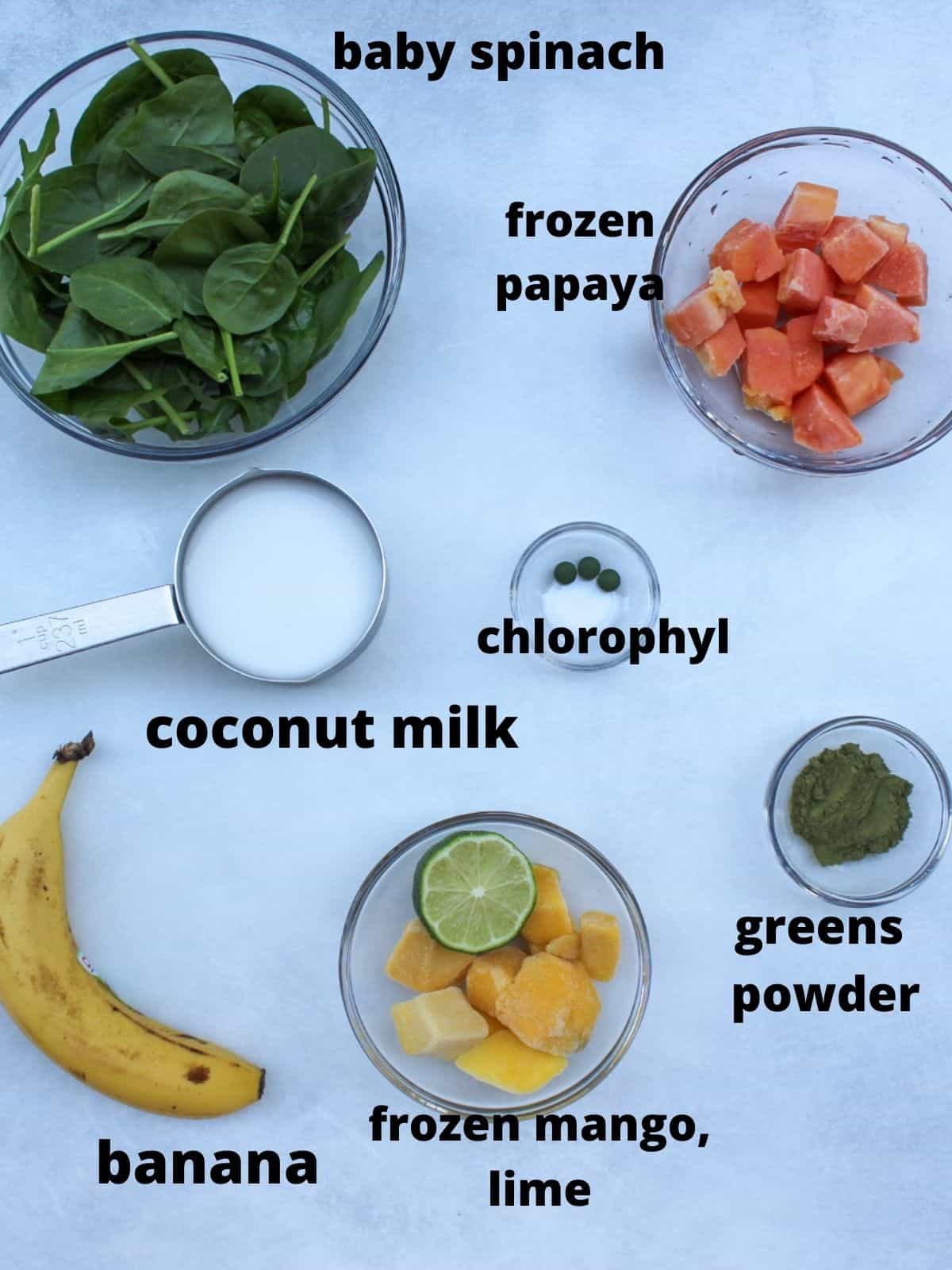 Papaya green smoothie labeled ingredients: spinach, frozen papaya, milk, chlotophyl, green powder, banana, frozen mango and a half og lime juice.