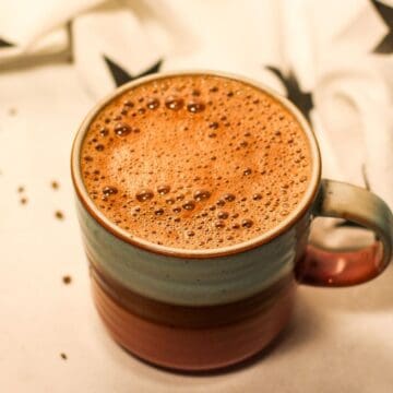 Overhead shot of a cup filled with hot chocolate. The chocolate looks frothy on top with some small bubbles.
