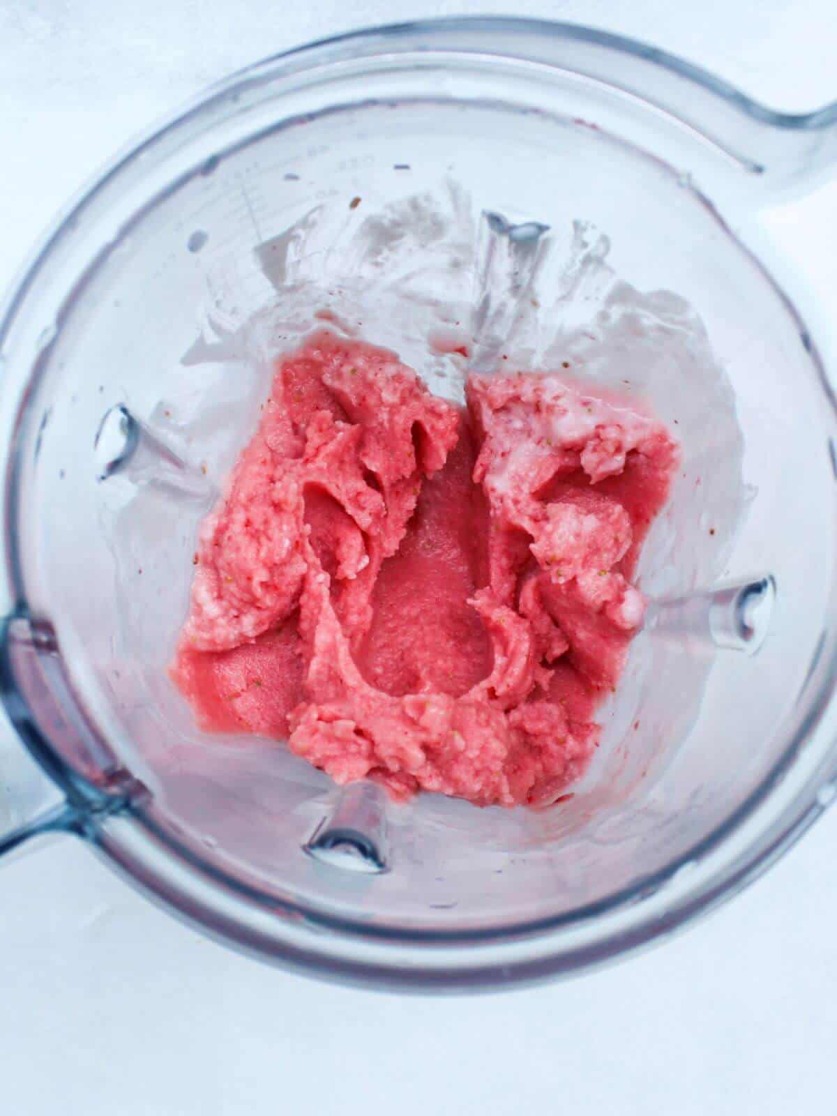 Overhead shot of a blender container with some pink thick blended smoothie.