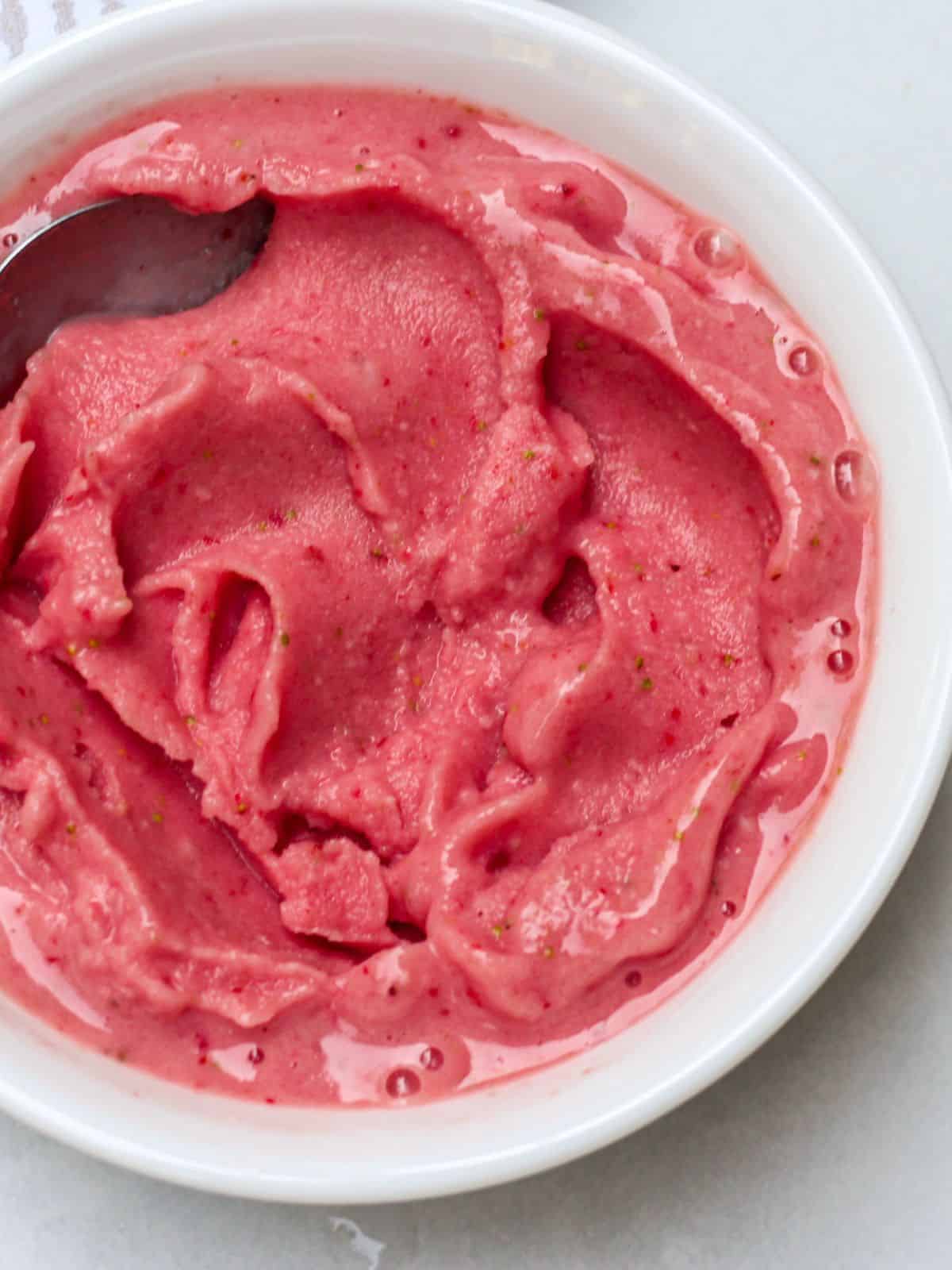 A white bowl filled with a thick blended fruit mass. It has pink color.