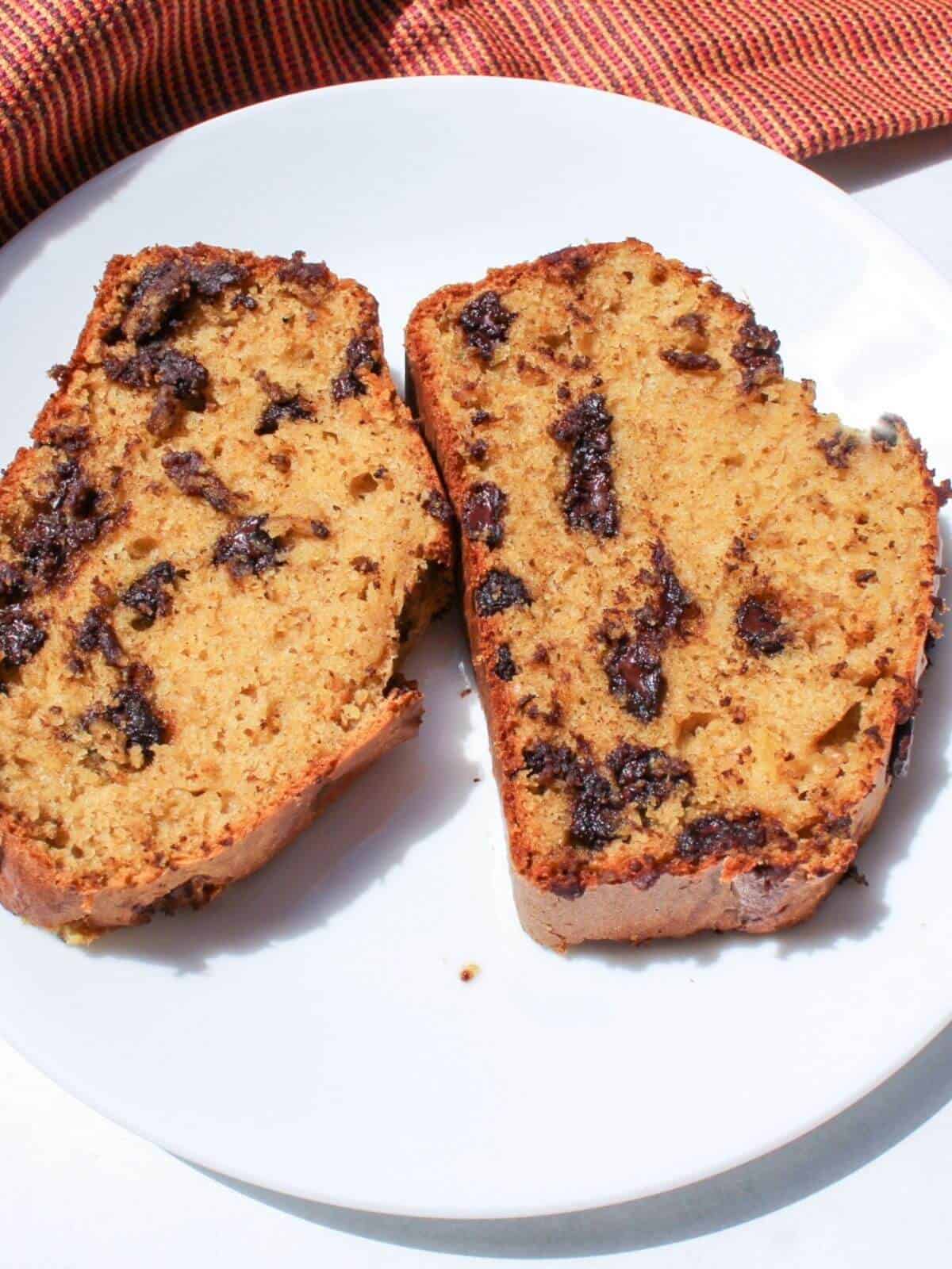 Overhead view of two slices of acorn squash bread laying flat on a white plate.