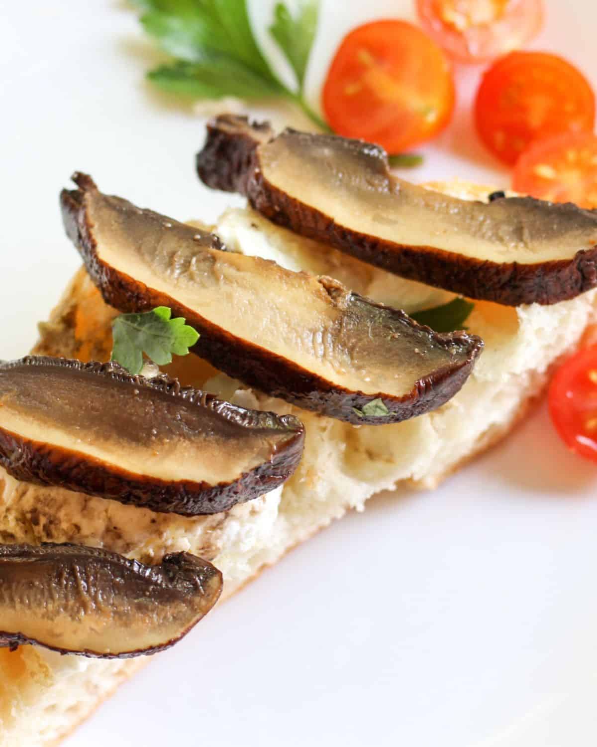 Bread with sliced cooked mushroom on top.