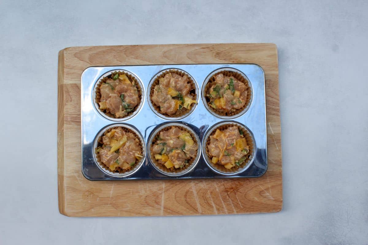 Stainless steel 6 muffin tin filled with the meat mix.