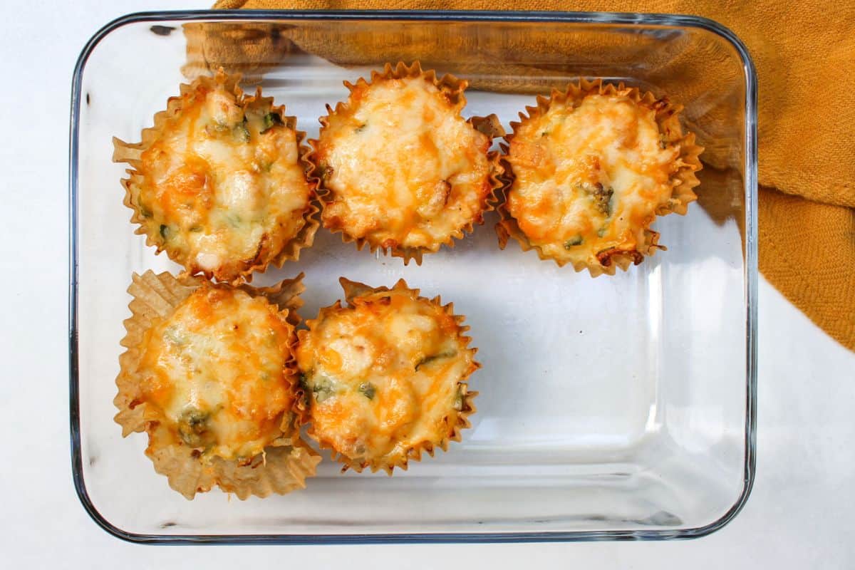 Overhead view of a glass containers with 5 golden muffins.