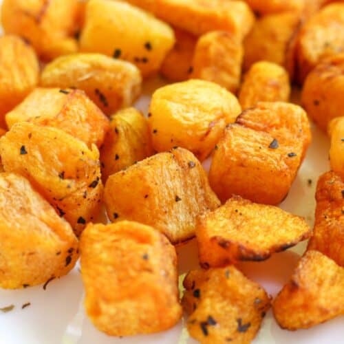 Close up shot of cubed roasted yellow vegetable with some specs of spices on top.