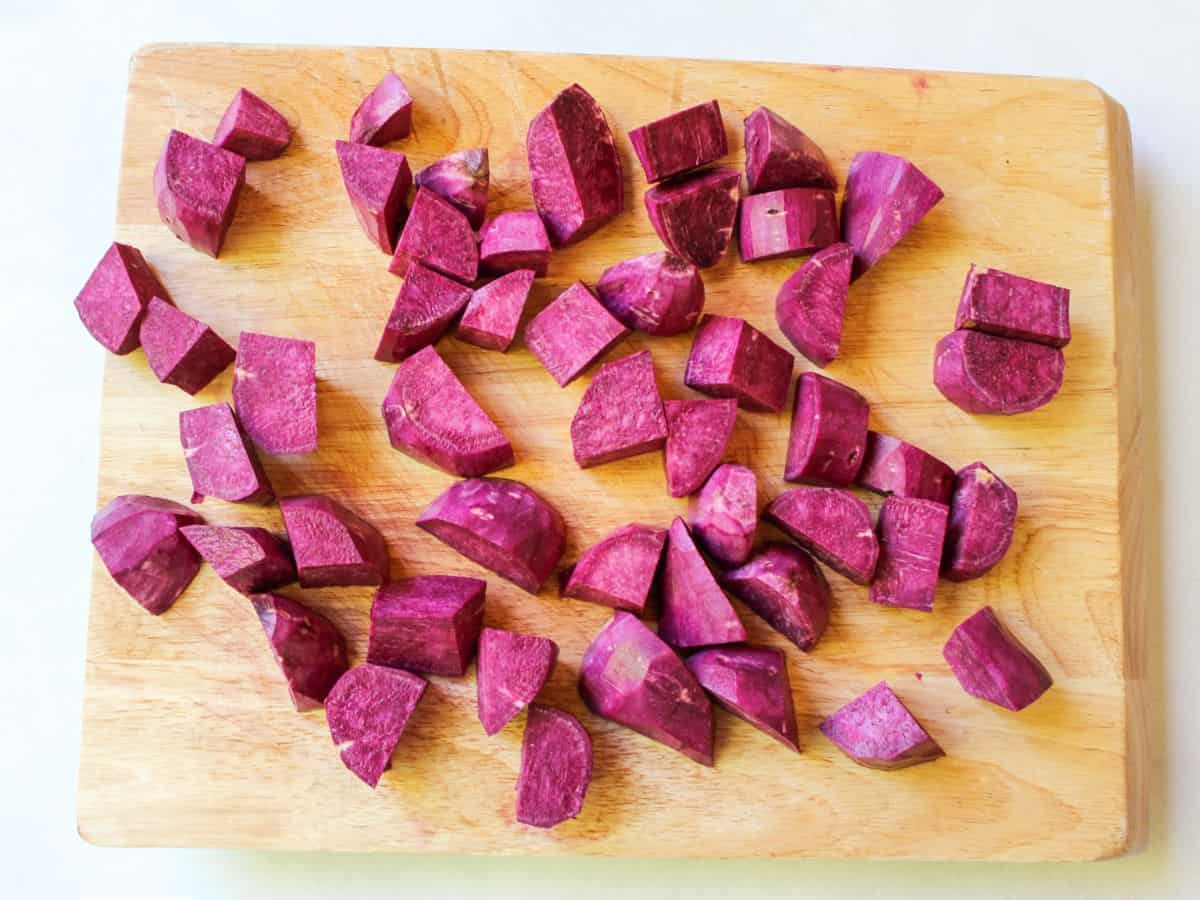 A cutting board with even-size chunks of purple vegetable.