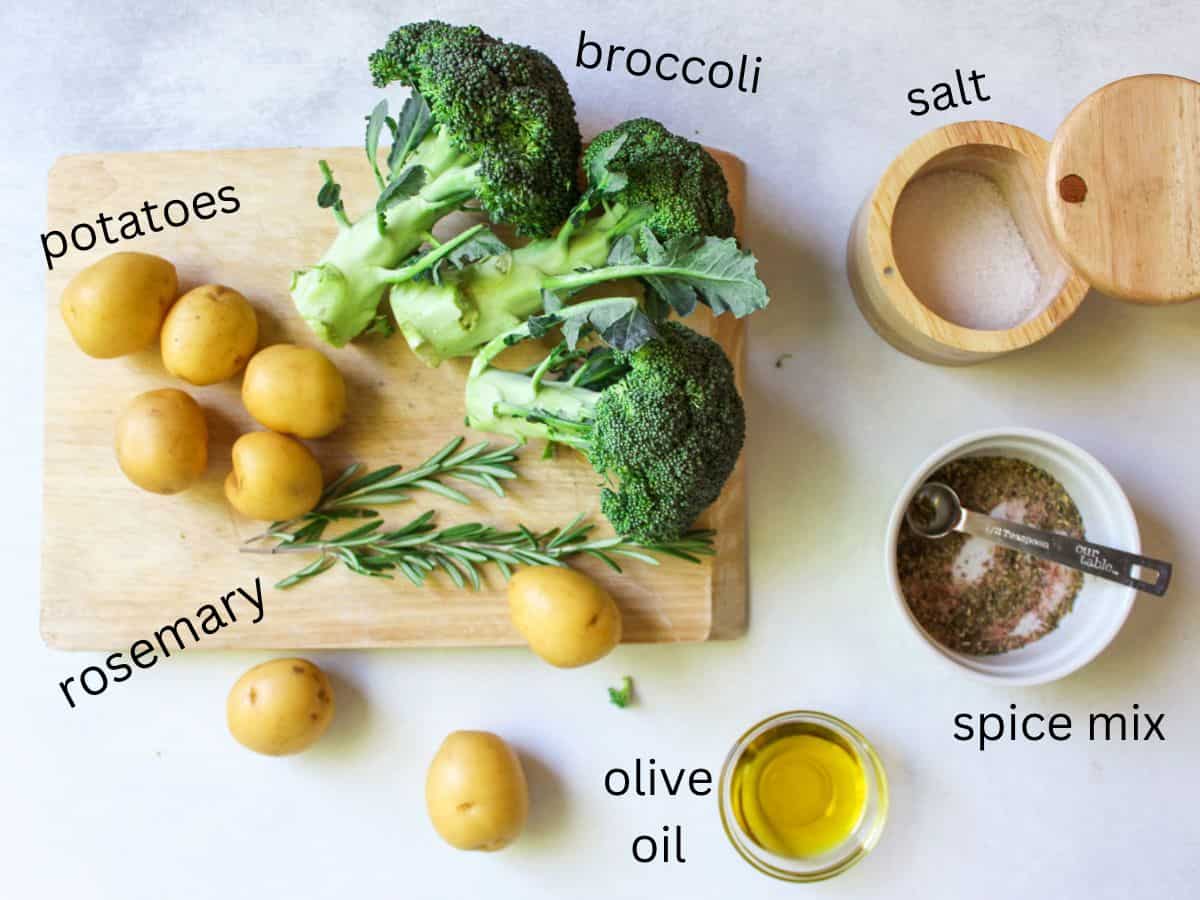 A recipe ingredients labeled on a white background. Broccoli, fresh rosemary and some of the potatoes are on a wooden cutting board.