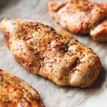 Cooked seasoned chicken breast on a parchment paper.