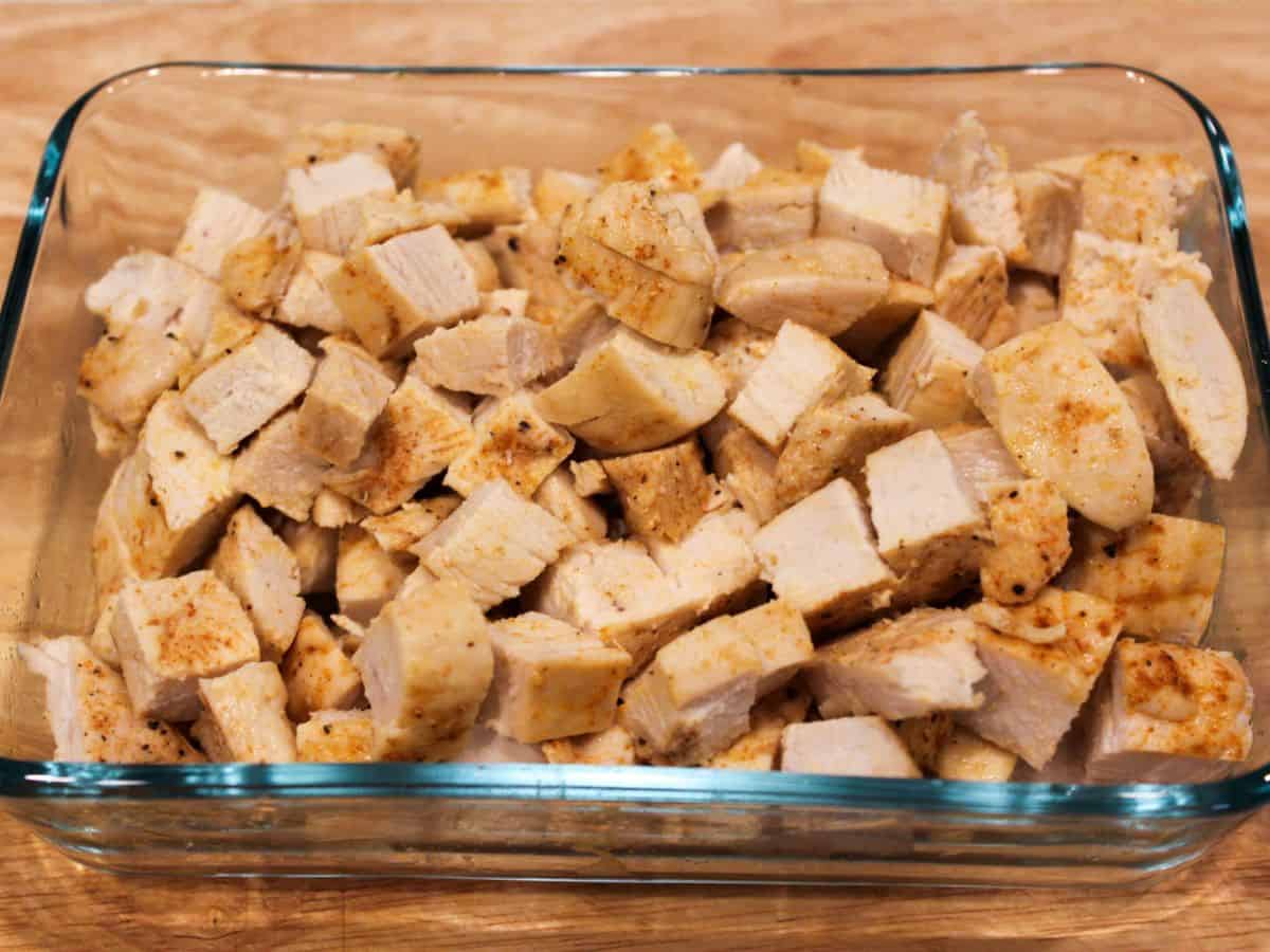 A glass container with cubed cooked chicken breasts.