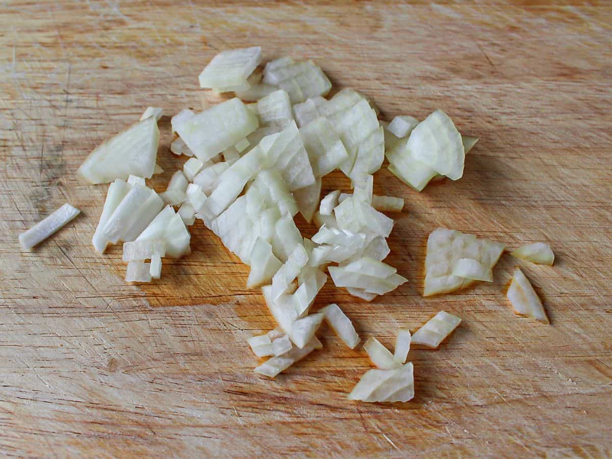 Finely diced onions on a wooden cutting board.