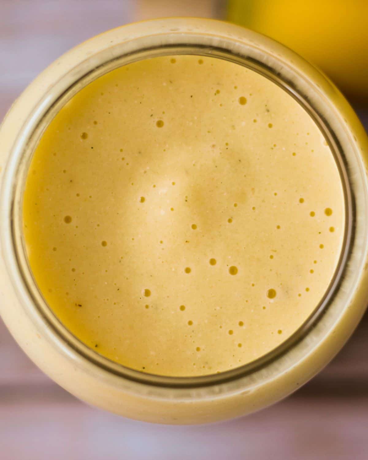 Overhead view of a glass filled with yellow-orange smoothie drink.