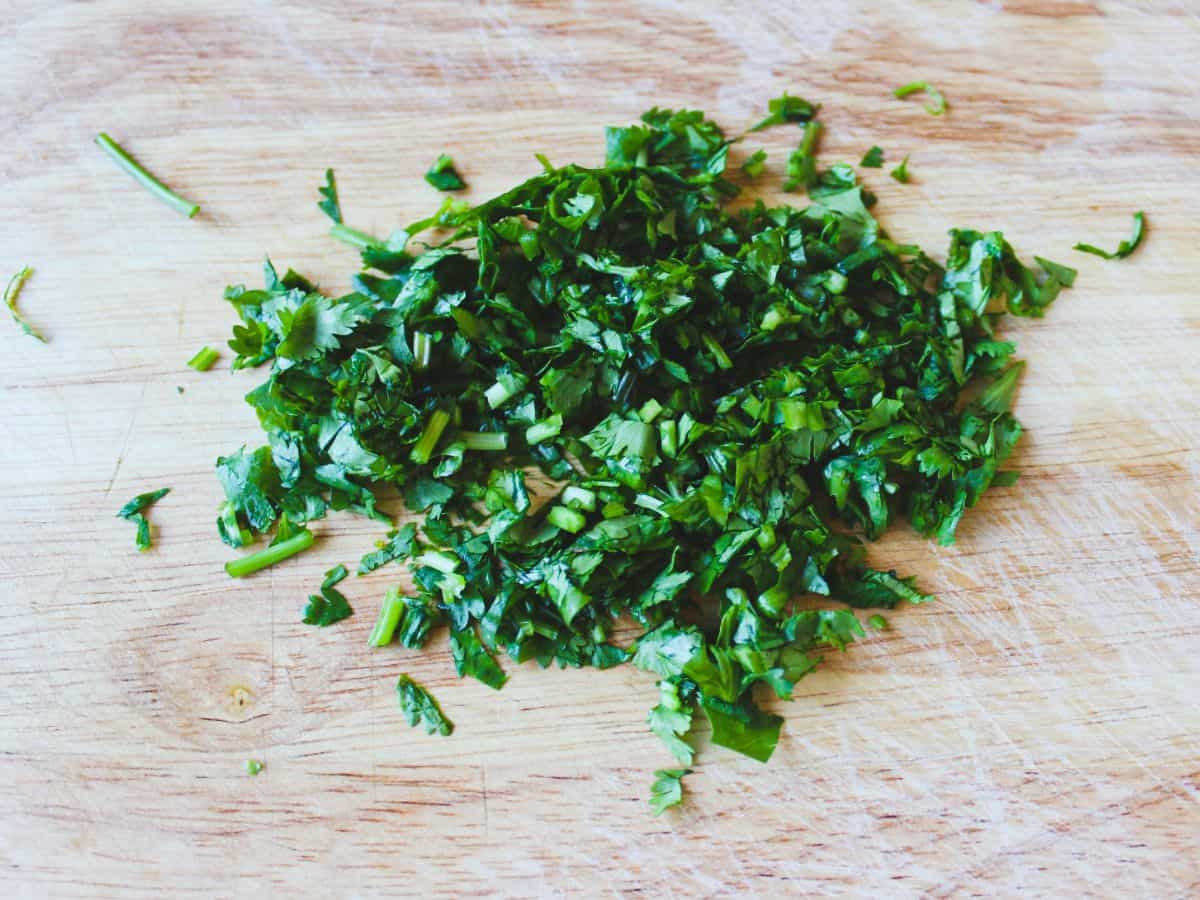 Finely chopped green cilantro on a cutting board.