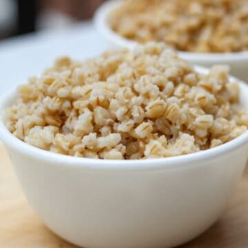 White bowl with cooked barley grain.